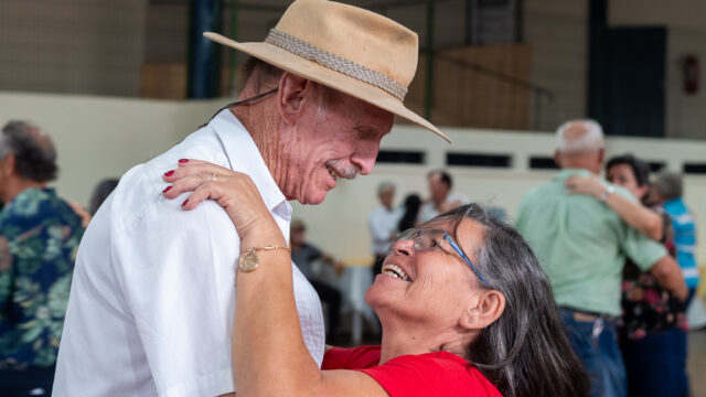 Homem com chapéu e camisa branca dança com mulher de blusa vermelha em evento do CECON Nova Rússia
