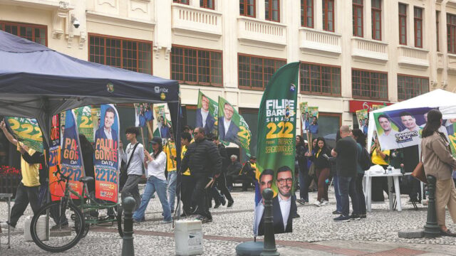 Bandeiras e cabos eleitorais em rua movimentada durante campanha política