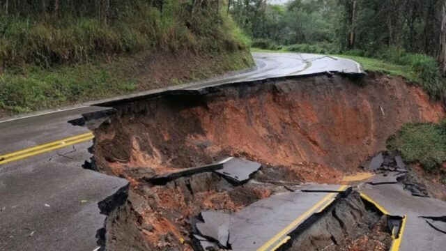Pista de rodagem asfaltada desmoronada devido a deslizamento de terra em área de encosta