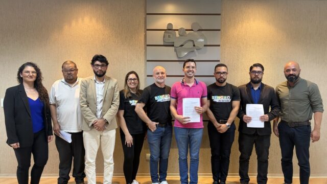 Grupo de nove pessoas posando lado a lado em sala de reunião da Câmara Municipal de Ponta Grossa