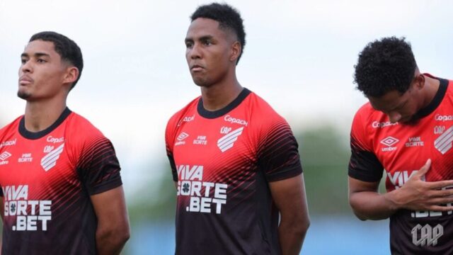 Três jogadores do Athletico com uniformes rubro-negros em atividade de futebol