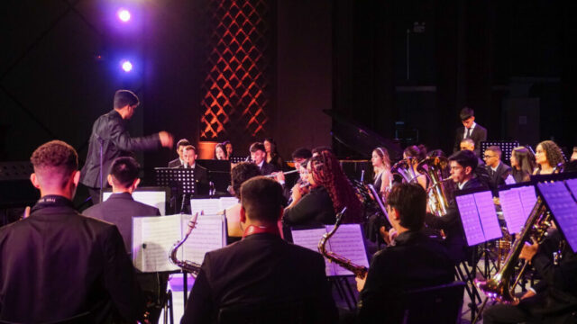 Músicos da Banda Escola Lyra dos Campos posicionados no palco com instrumentos durante ensaio em Ponta Grossa