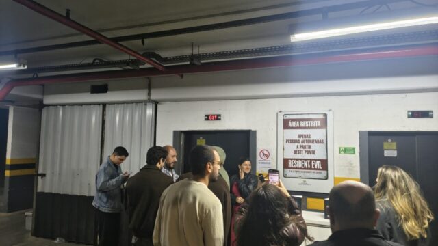 Pessoas aguardam em pé perto de elevadores com sinalização de área restrita no Shopping Jardim das Américas