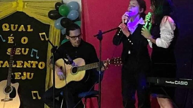 Participantes cantam e tocam violão no palco em evento do show de talentos em Castro