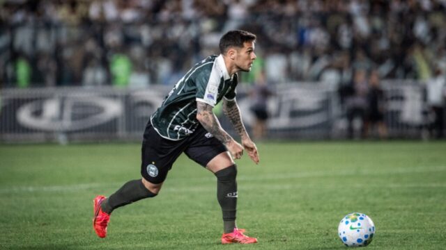 Jogador com camisa listrada verde e branca do Coritiba corre pelo gramado com a bola