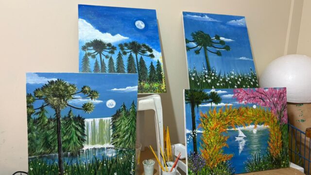 Quadros de pintura a óleo retratando araucárias e paisagens naturais em um ateliê