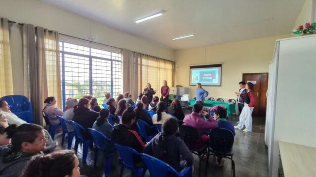 Pessoas sentadas em cadeiras em uma sala de aula acompanhando palestra sobre Direito Eleitoral