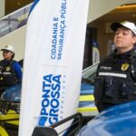 Agentes de trânsito fardados com bonés e viaturas em exposição durante evento em shopping