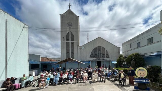 Idosos reunidos no pátio em frente à fachada do Asilo São Vicente de Paulo em Ponta Grossa