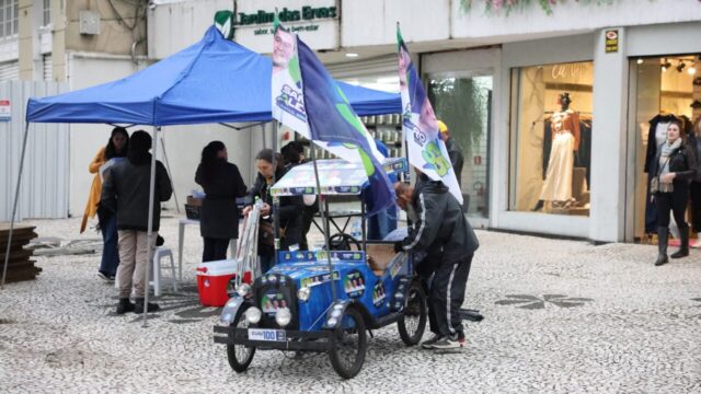 Carrinho de campanha política enfeitado com bandeiras e materiais eleitorais em calçadão de Curitiba