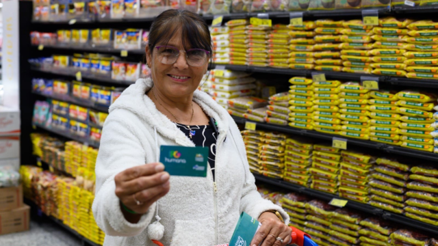 Mulher sorridente segura o Cartão PG Humana em um supermercado em Ponta Grossa