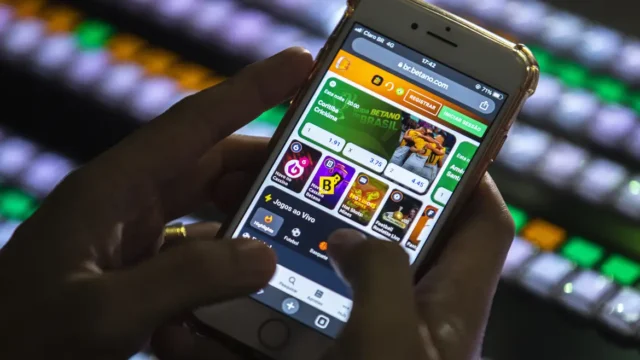 Pessoa manuseia um smartphone exibindo a interface de um site de apostas online