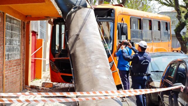 Ônibus laranja e poste derrubado na fachada de imóvel comercial isolado por fita de segurança