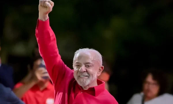Presidente Luiz Inácio Lula da Silva com camisa vermelha e punho erguido em gesto político