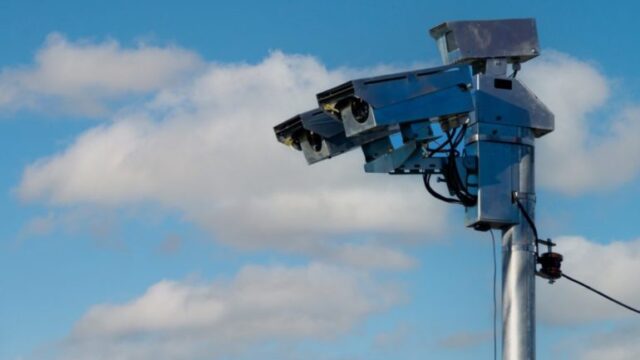 Equipamento de fiscalização de trânsito instalado em poste às margens de rodovia no Paraná sob céu azul