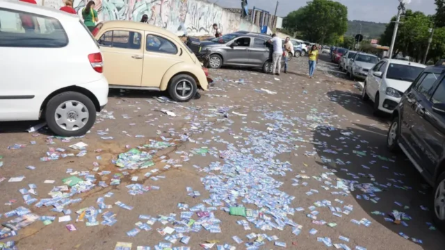 Rua repleta de panfletos eleitorais espalhados no chão entre carros estacionados