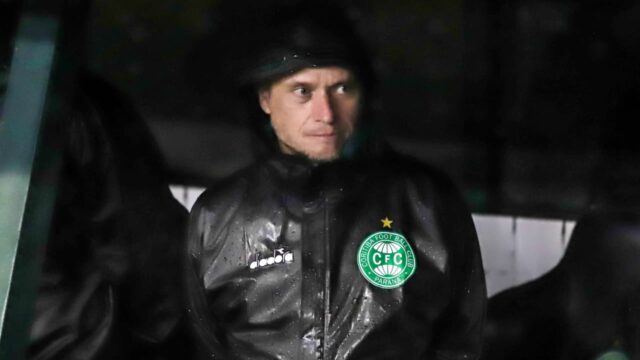 Técnico Fernando Seabra com casaco impermeável preto com o escudo do Coritiba em jogo sob chuva