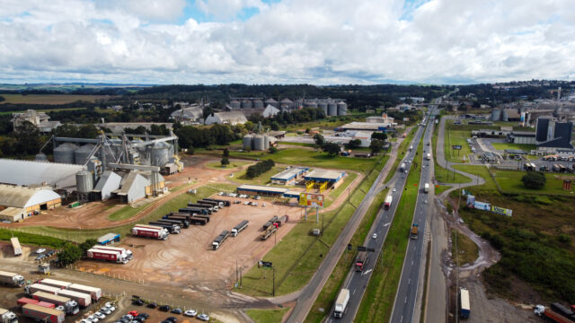 Vista aérea de silos de armazenamento de grãos, caminhões estacionados e rodovia em Ponta Grossa