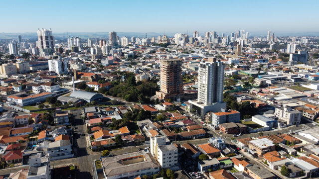 Vista aérea parcial de Ponta Grossa com prédios e ruas residenciais sob céu azul