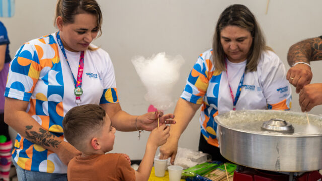 Menino recebendo algodão-doce de funcionárias em evento da FASPG em Ponta Grossa
