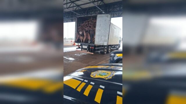 Caminhão com baú aberto revelando carga de móveis abordado pela PRF em rodovia