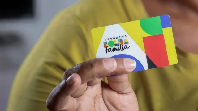 Pessoa segura cartão do programa Bolsa Família nas mãos