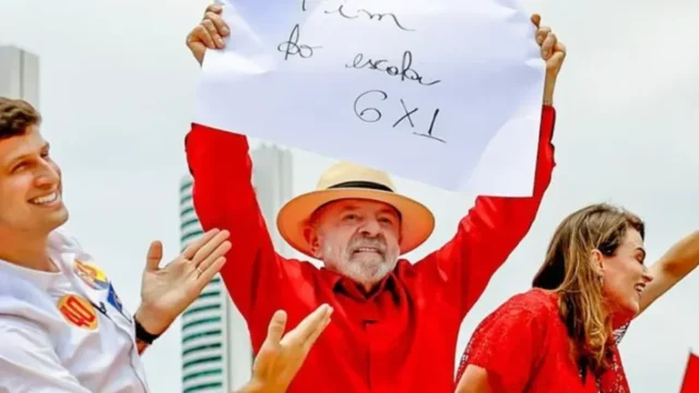 O presidente Lula segura um cartaz que pede o fim da escala 6x1 cercado por apoiadores em evento político