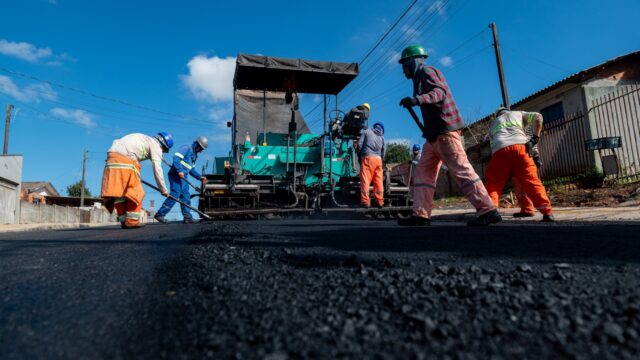 Equipe de trabalhadores aplicando asfalto em rua de Ponta Grossa durante serviços de pavimentação