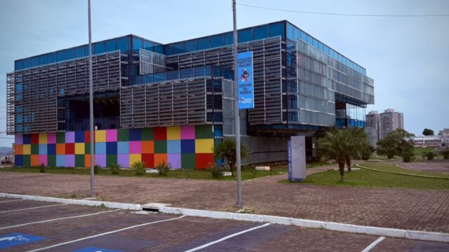 Fachada moderna do Conservatório Maestro Paulino com painel colorido no térreo e janelas de vidro em Ponta Grossa