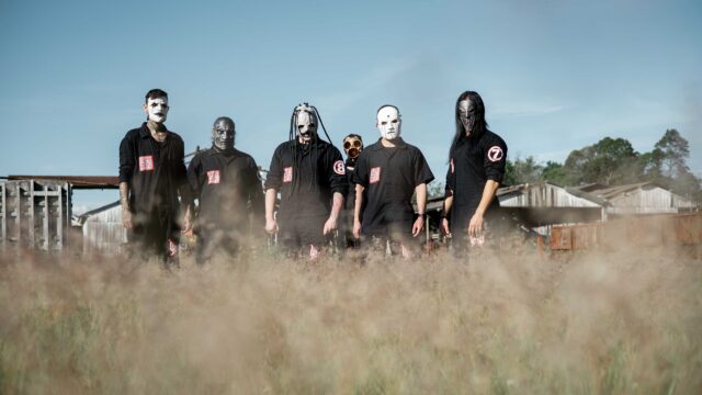 Integrantes da banda Hellshade com máscaras e macacões pretos em campo aberto