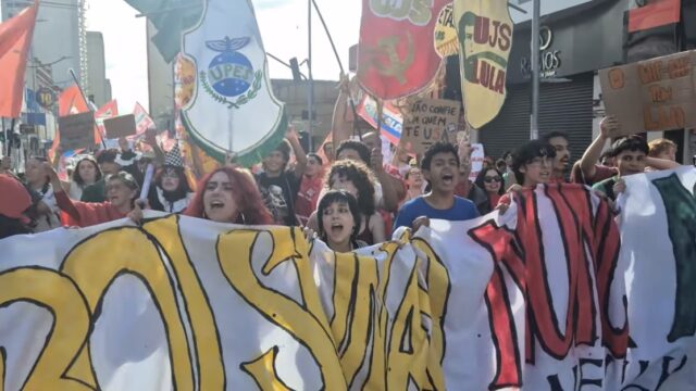 Manifestantes reunidos no Ponto Azul em Ponta Grossa segurando faixas e bandeiras durante ato político