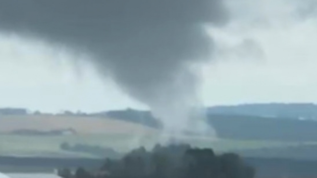 Nuvem em formato de funil de tornado tocando a copa de árvores em área rural dos Campos Gerais