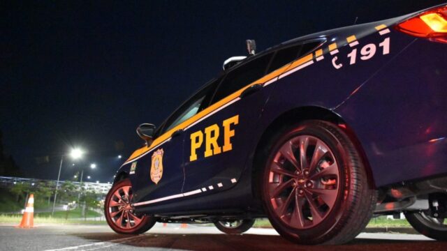 Viatura da Polícia Rodoviária Federal parada em rodovia durante a noite com giroflex ligado