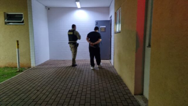 Homem algemado e policial militar em área externa de residência
