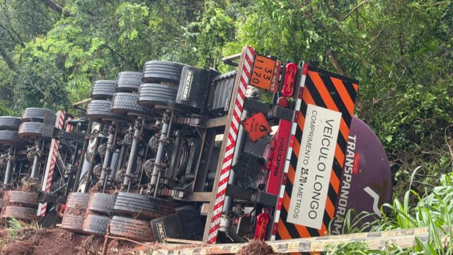 Caminhão bitrem tombado com as rodas para cima na beira da rodovia em Juranda
