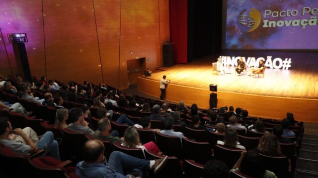 Plreia de auditório com público assistindo a painel no palco