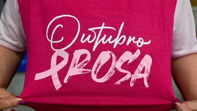 Pessoa segura camiseta rosa com a frase Outubro Rosa estampada em destaque
