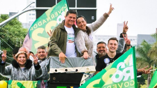 Grupo de políticos e apoiadores acenando em cima de um veículo durante carreata em Ponta Grossa