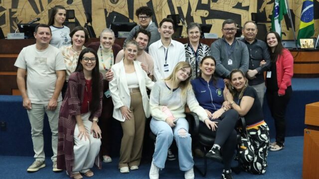 Grupo de servidores públicos sorri posando para foto no plenário da Câmara Municipal de Ponta Grossa