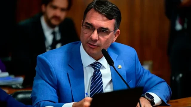 Senador Flávio Bolsonaro usa terno azul e óculos enquanto discursa em sessão no Senado Federal