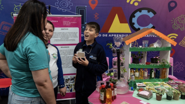 Estudantes e professora conversam junto a maquete e plantas em feira escolar em Ponta Grossa