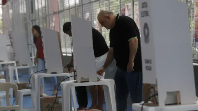 Eleitores utilizando urnas eletrônicas em seção eleitoral durante o dia de votação