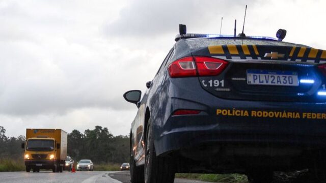 Viatura da Polícia Rodoviária Federal estacionada no acostamento de rodovia com o giroflex ligado