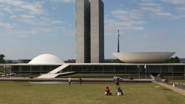 Fachada do prédio do Congresso Nacional em Brasília sob um céu azul com nuvens