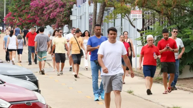 Pessoas caminhando por calçada em dia ensolarado