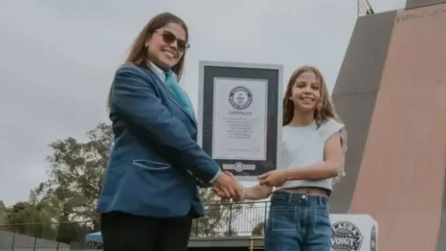 Menina Laura Voigt segurando certificado do Guinness World Records ao lado de representante oficial em Curitiba