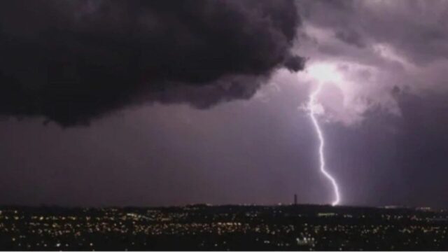 Relâmpago brilhante iluminando nuvens escuras de tempestade sobre área urbana à noite