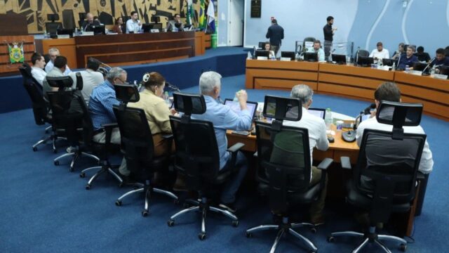 Vereadores sentados em mesas semicirculares durante sessão na Câmara Municipal de Ponta Grossa